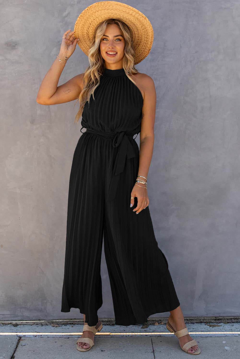 Black halter-neck pleated wide-leg jumpsuit with belt.