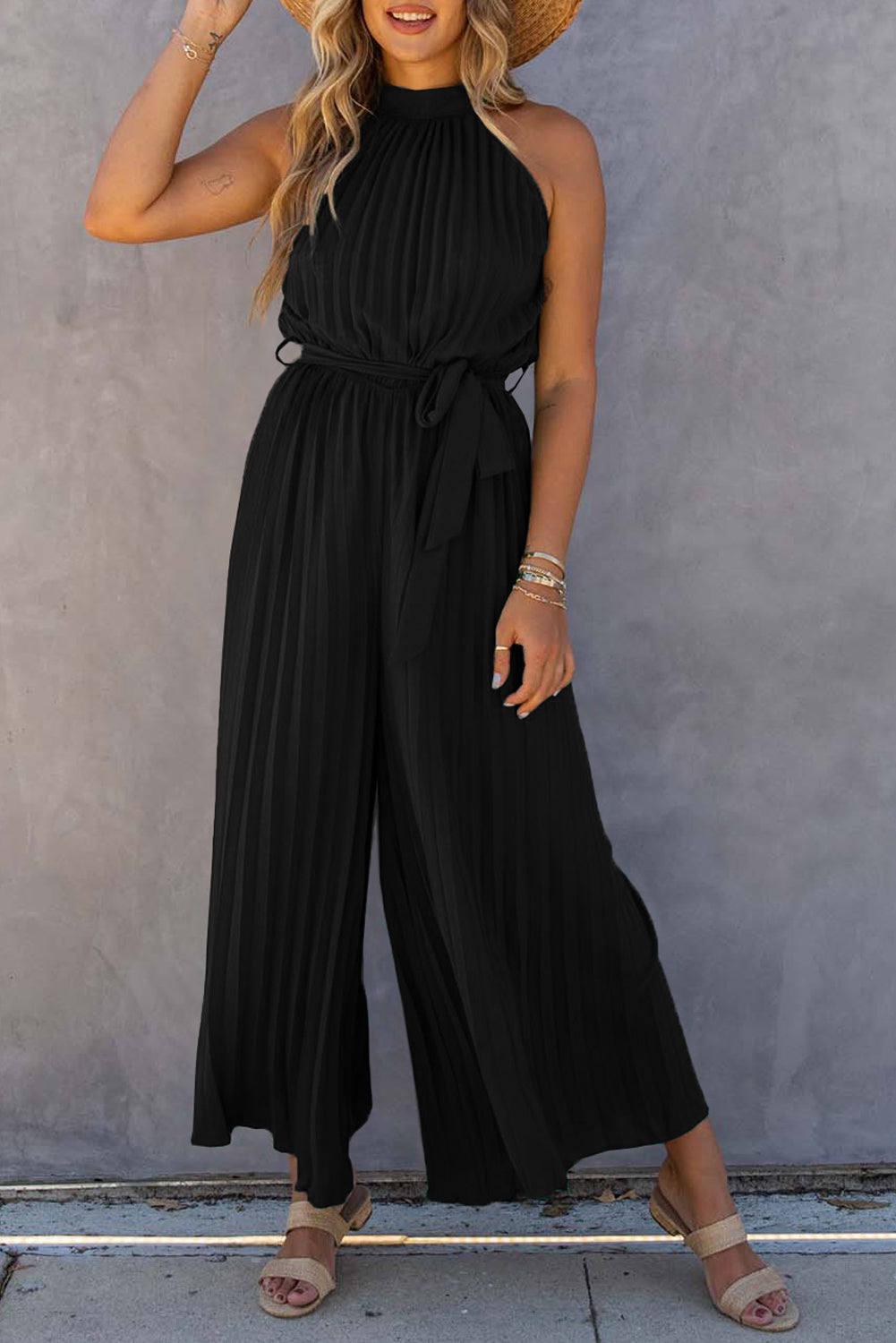 Black halter-neck pleated wide-leg jumpsuit with belt.
